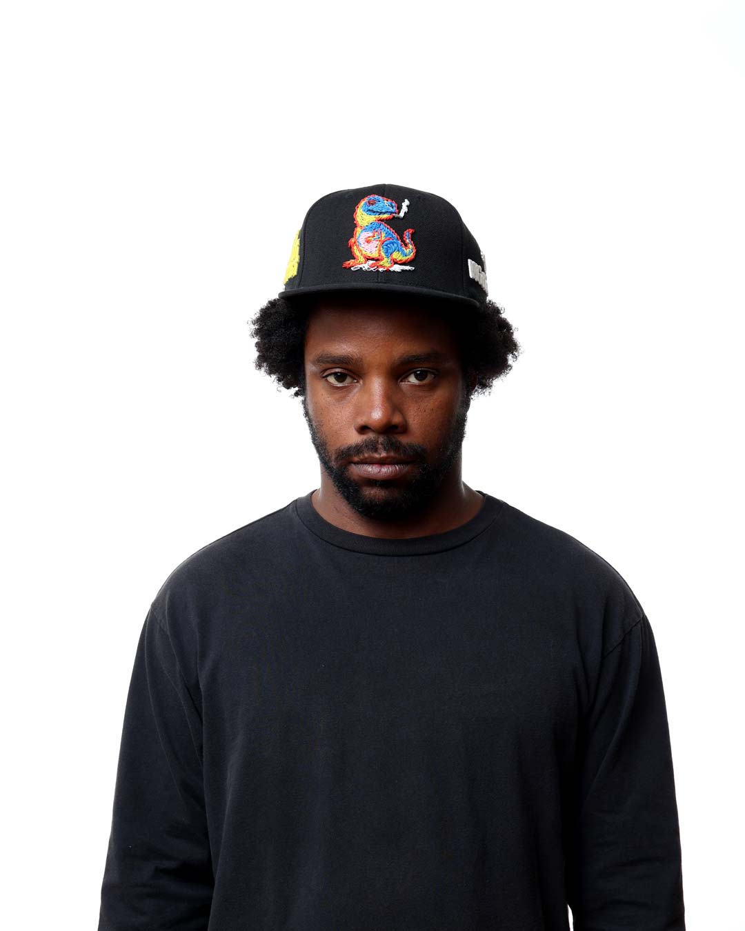 Person wearing a black cap with colorful design on a white background