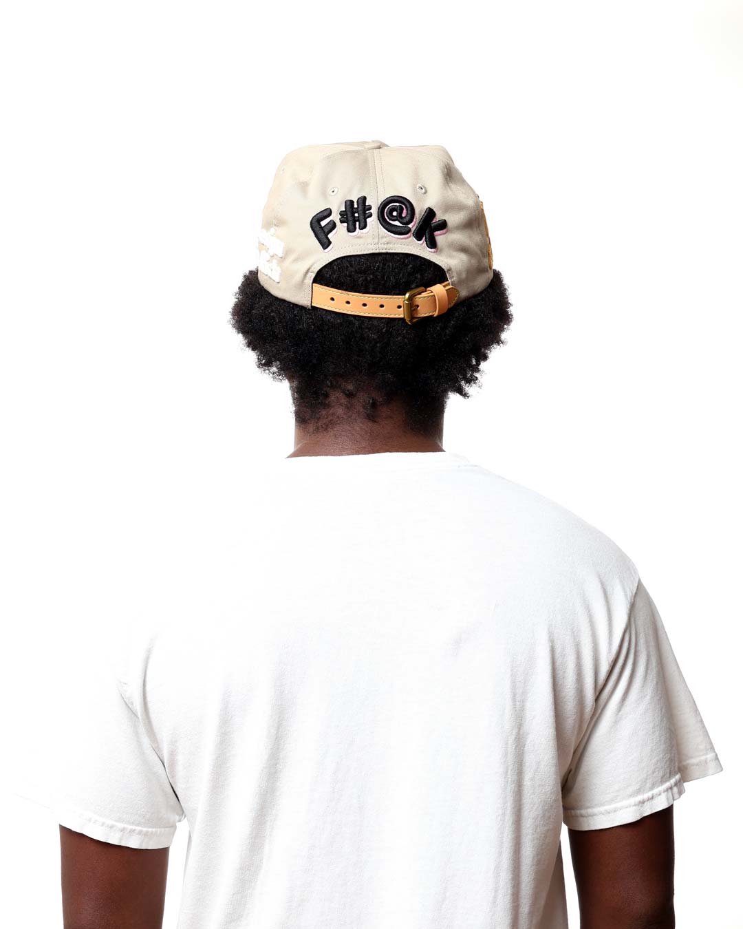 Person wearing a beige cap with black text and a white t-shirt on a white background