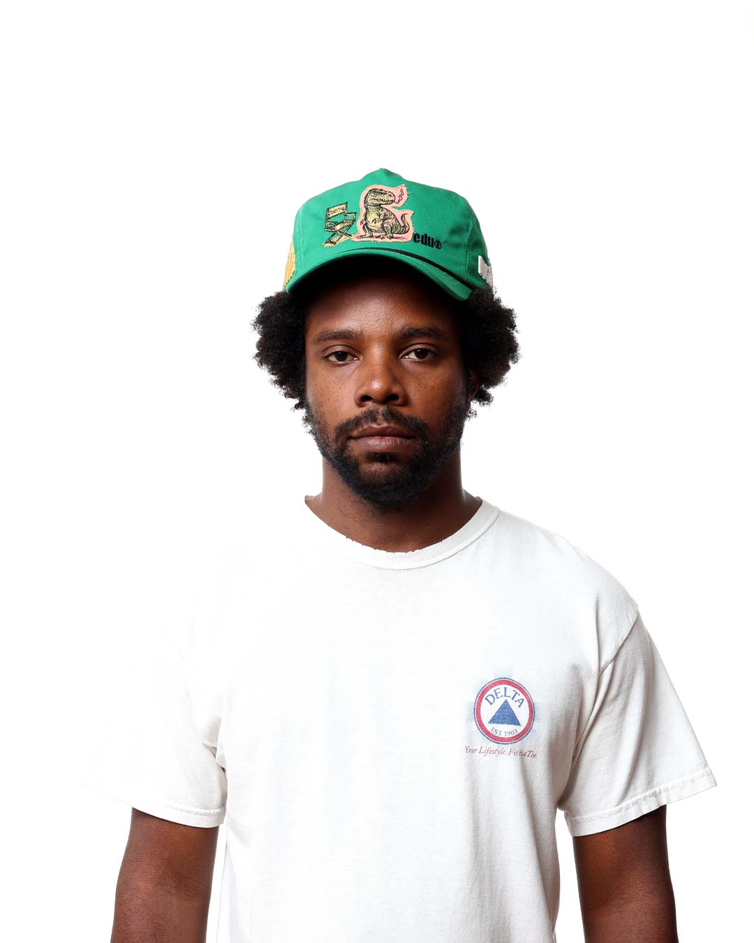 Man wearing a green cap and white t-shirt with a logo on a white background
