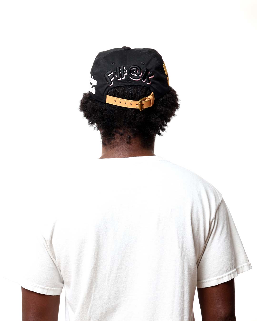 Person wearing a black cap with gold accents on a white background