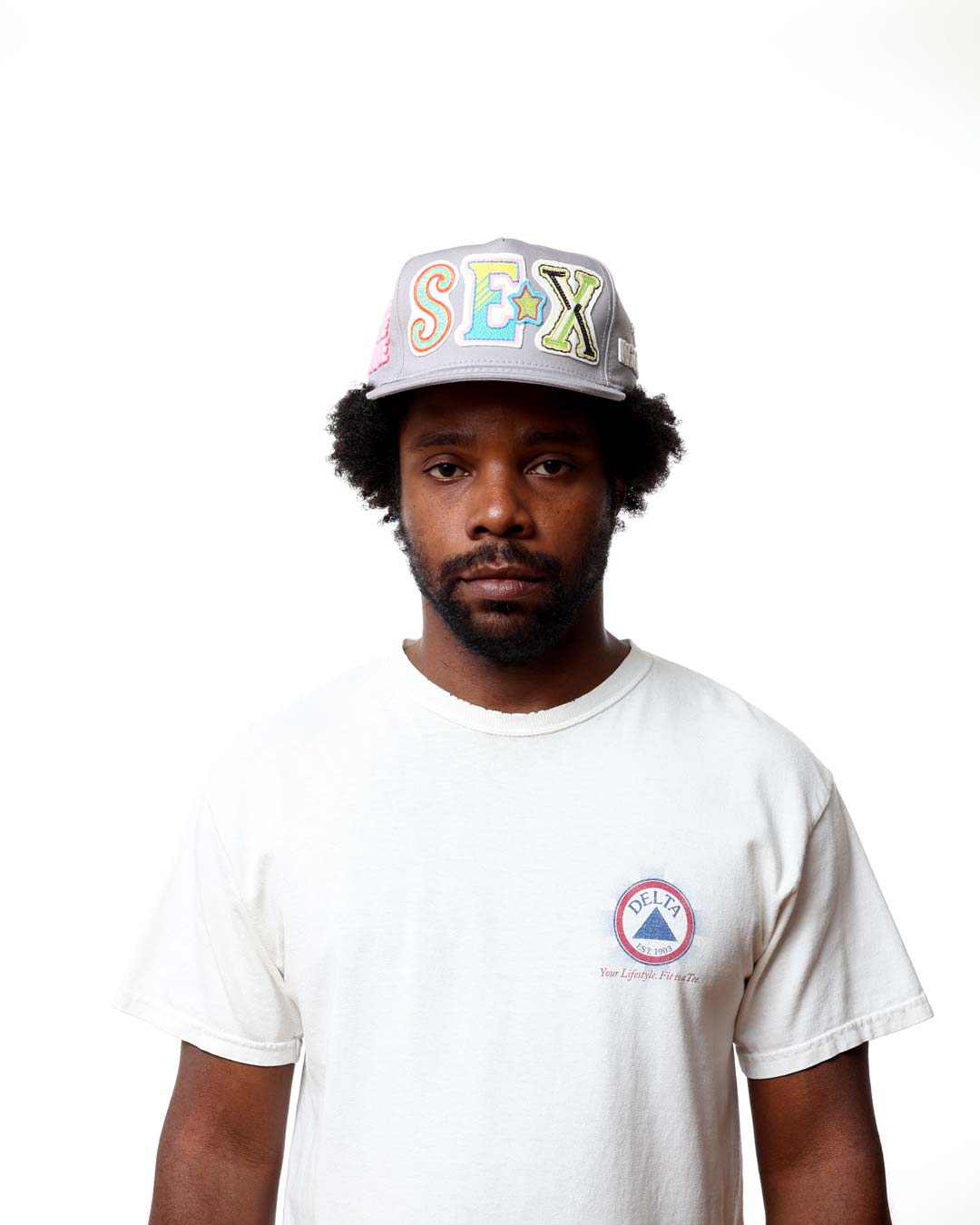 Person wearing a cap with colorful text and a white t-shirt with a logo on a white background