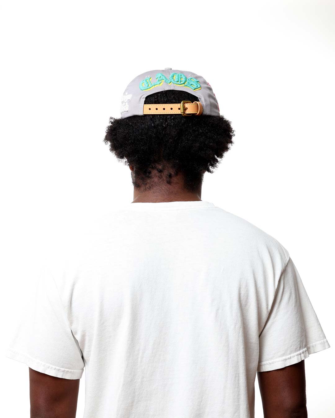 Person wearing a white cap with colorful text and a white t-shirt on a white background