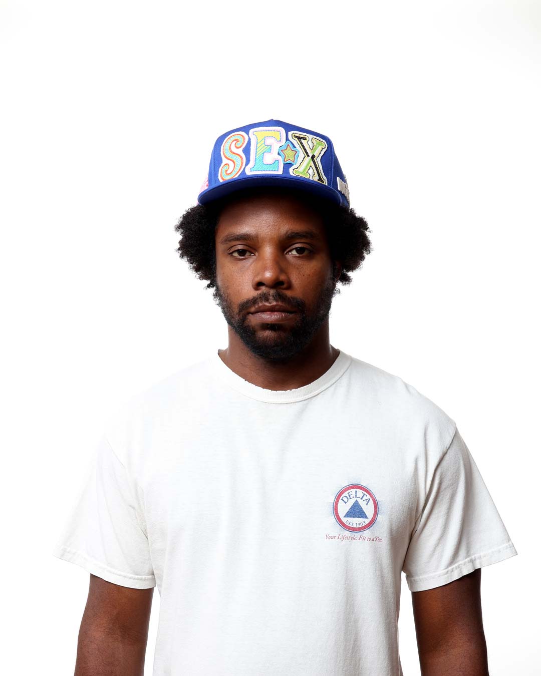 Man wearing a white t-shirt with a logo and a colorful cap on a white background