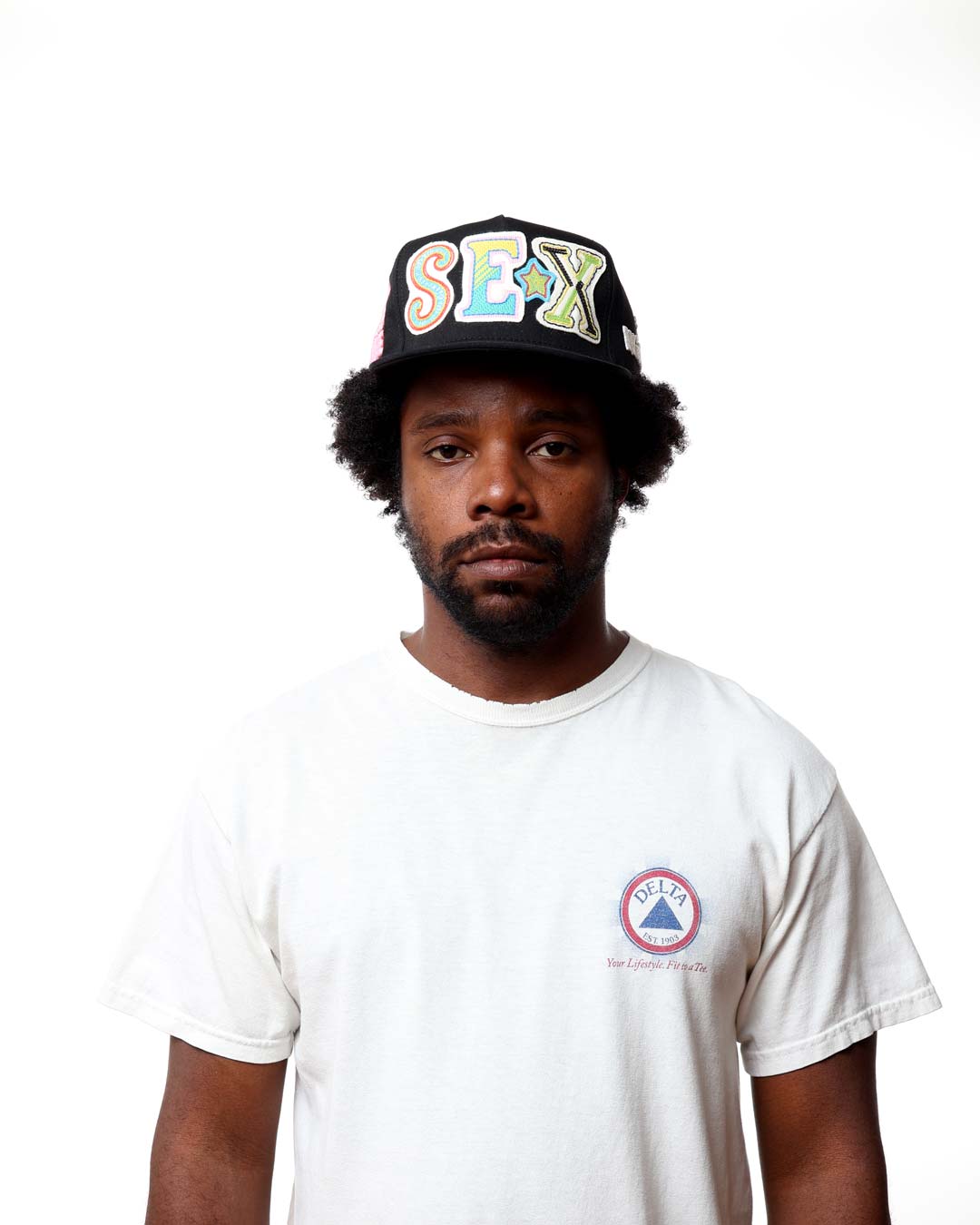 Person wearing a cap with colorful text and a white t-shirt with a logo on a white background