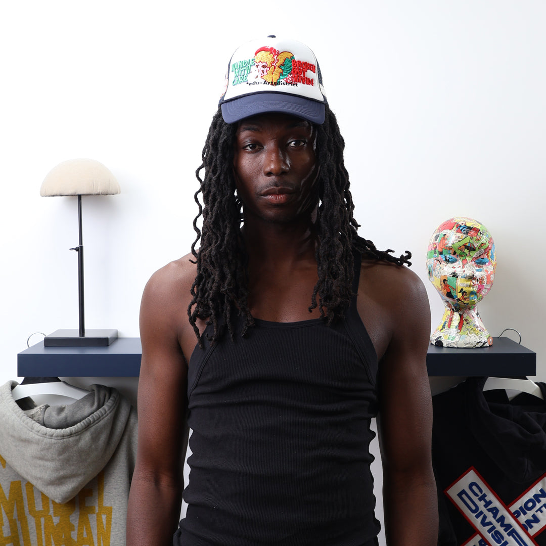 Young man in black tank top, colorful cap in art room.