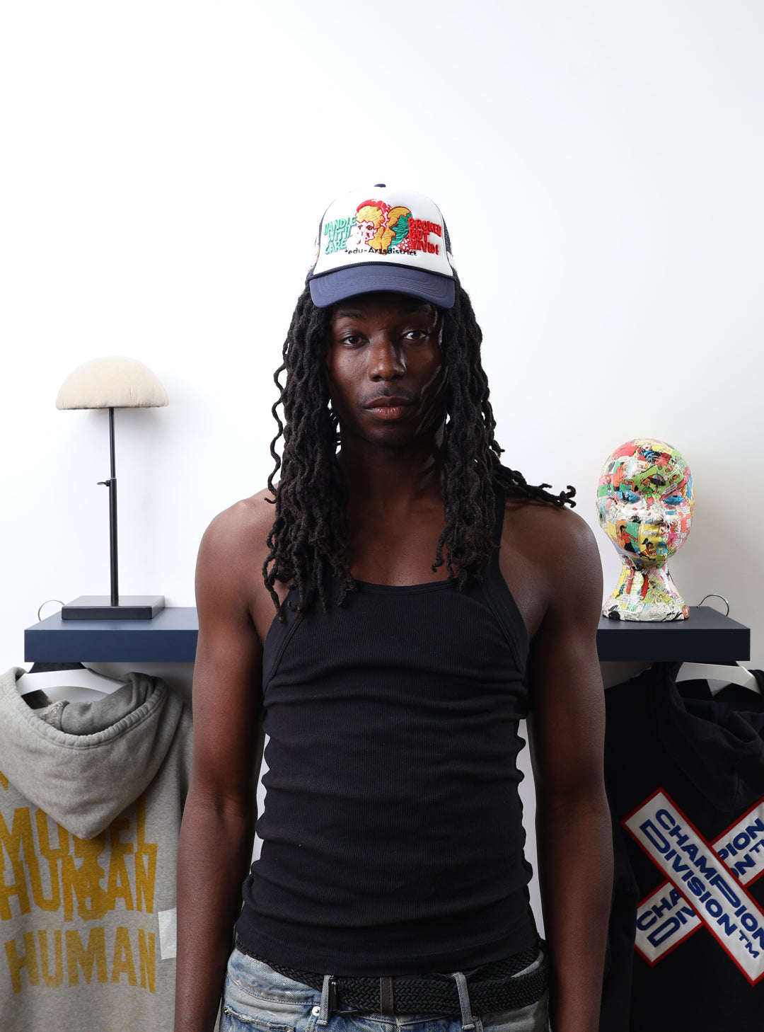 Young man in black tank top, colorful cap in art room.