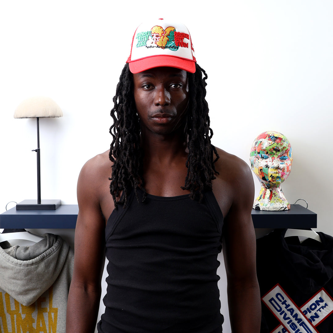 Man in red cap and black tank top near clothing display.