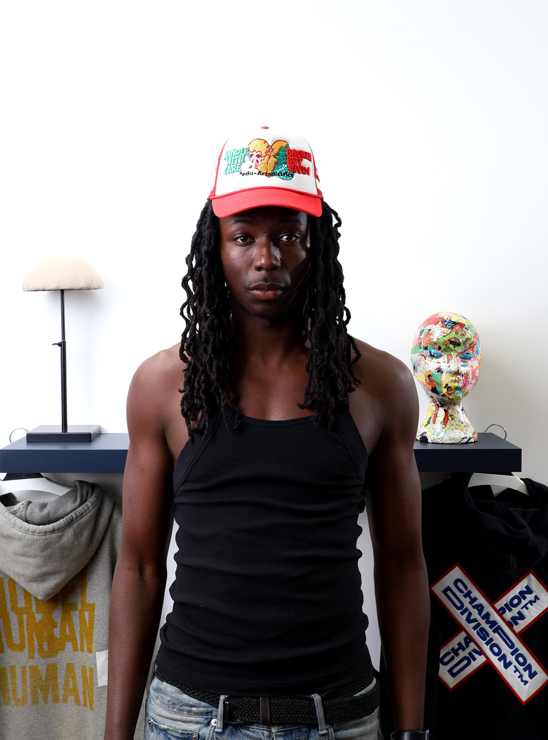 Man in red cap and black tank top near clothing display.