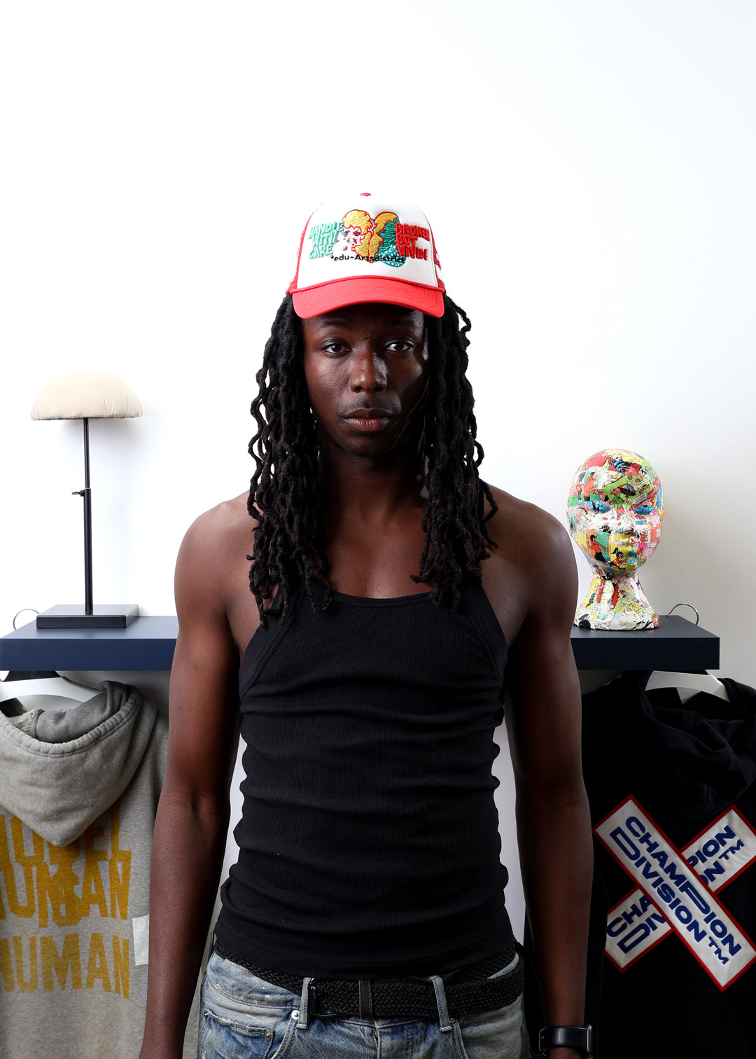 Man in red cap and black tank top near clothing display.