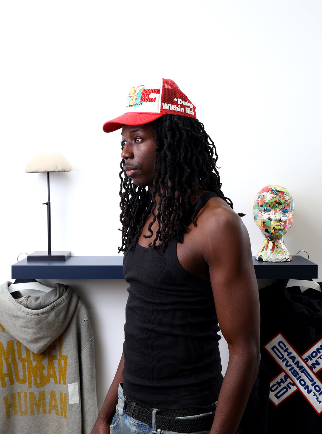 Man in red cap, black tank top, near shelf.