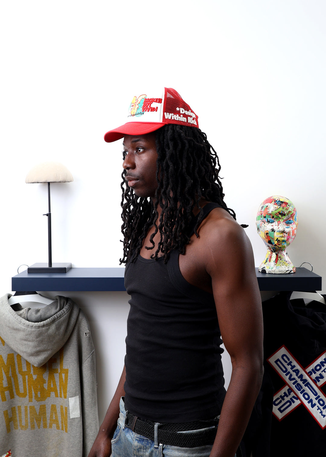 Man in red cap, black tank top, near shelf.