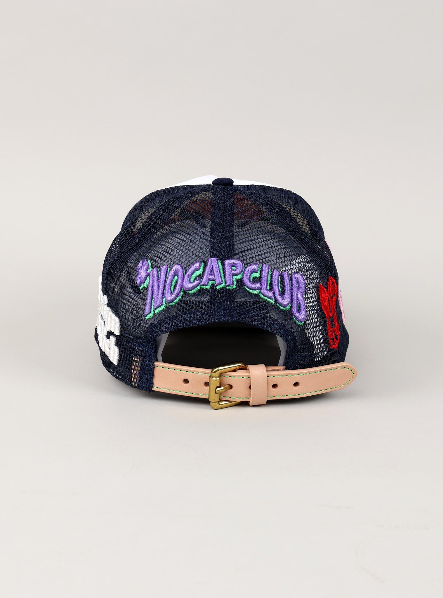 Navy mesh cap with "NOCAPCLUB" text, tan strap.