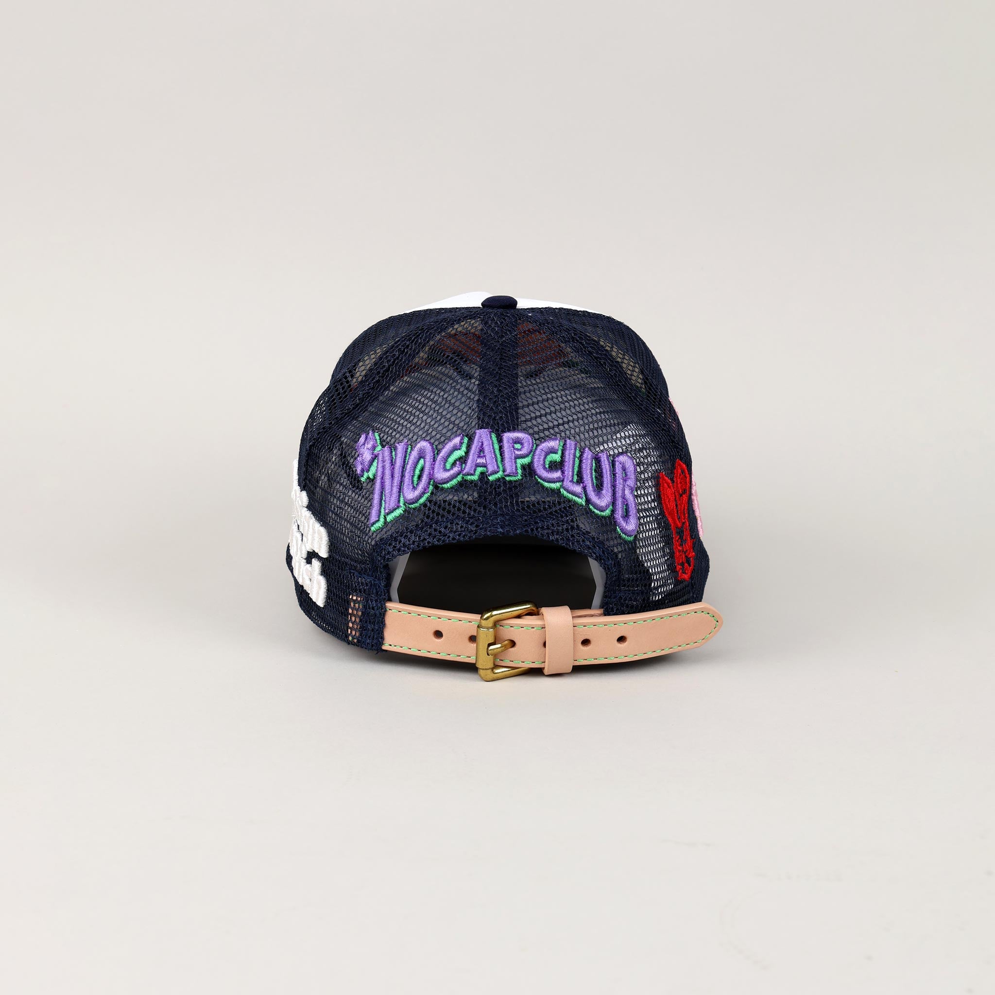 Navy mesh cap with "NOCAPCLUB" text, tan strap.