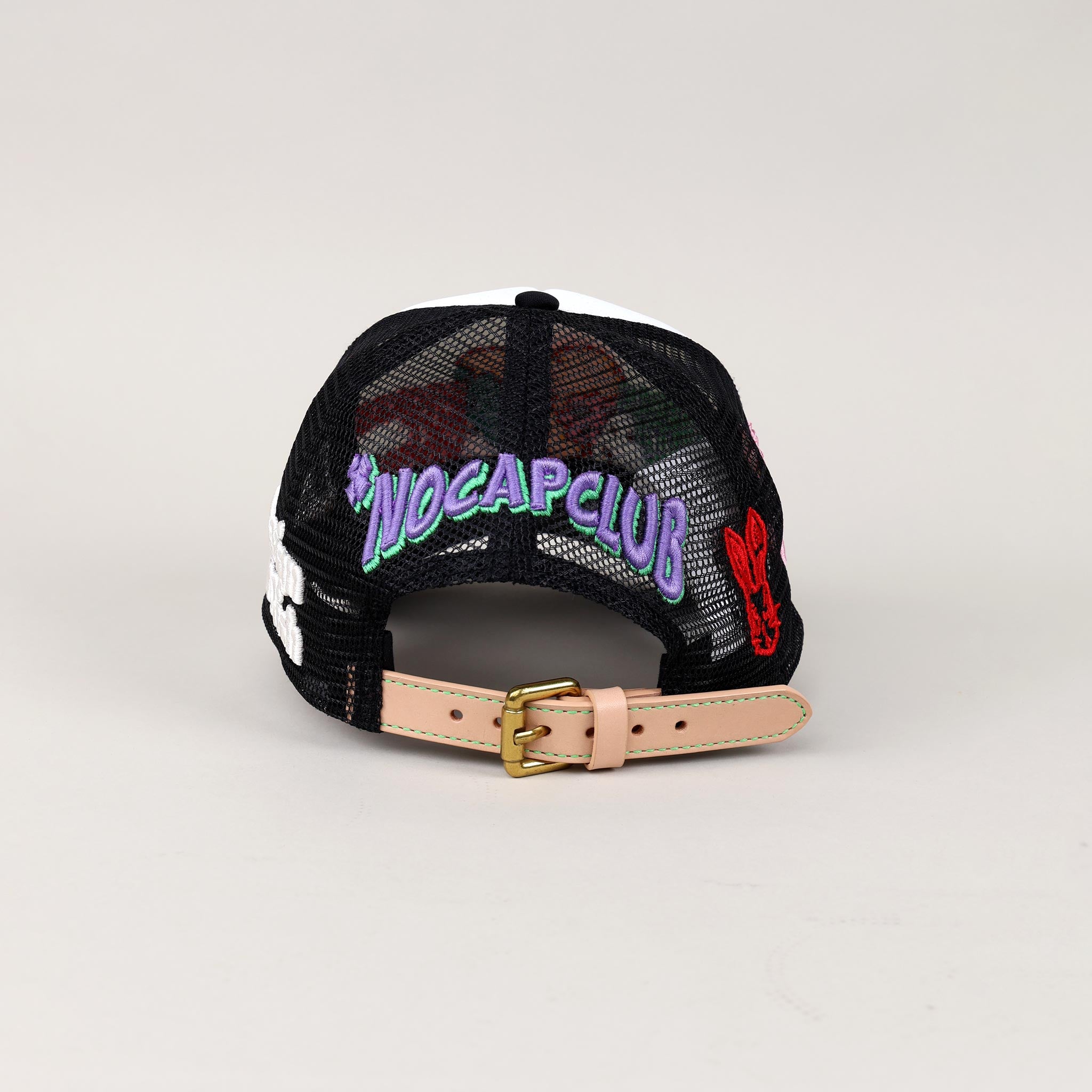 Black mesh cap with "NOCAPCLUB" text, colorful patches.