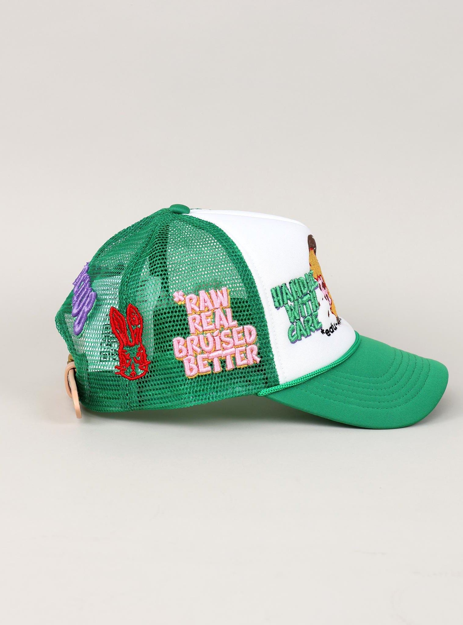 Green and white trucker hat with embroidered patches.
