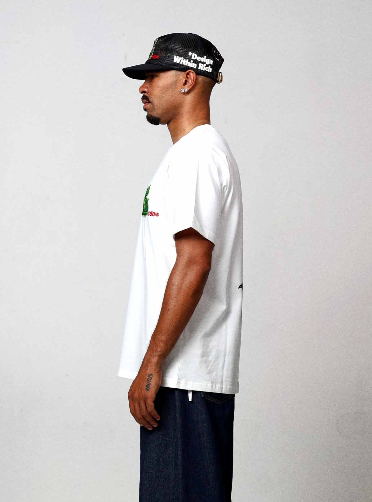 Man in white t-shirt and cap, side view.