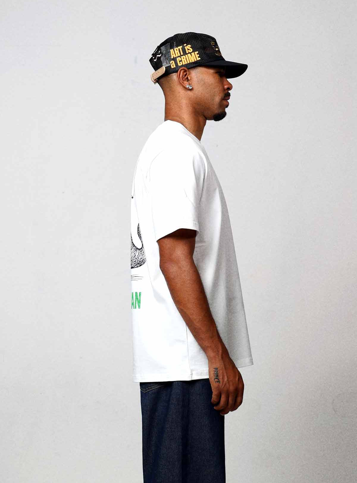 Man in white t-shirt and cap, side view.