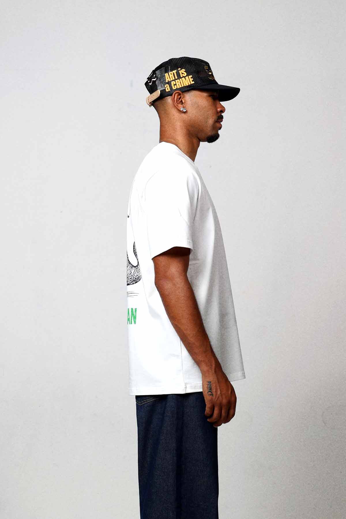 Man in white t-shirt and cap, side view.
