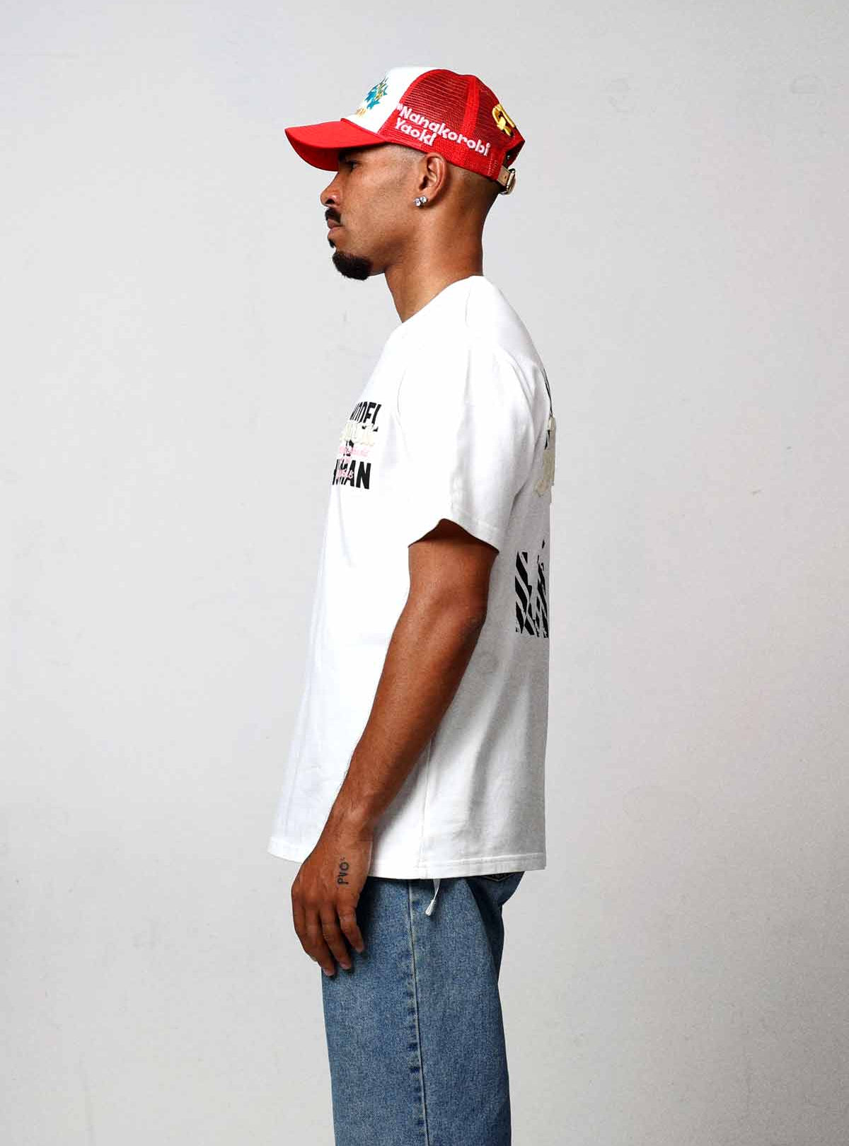 Man in white shirt and red cap, side view.