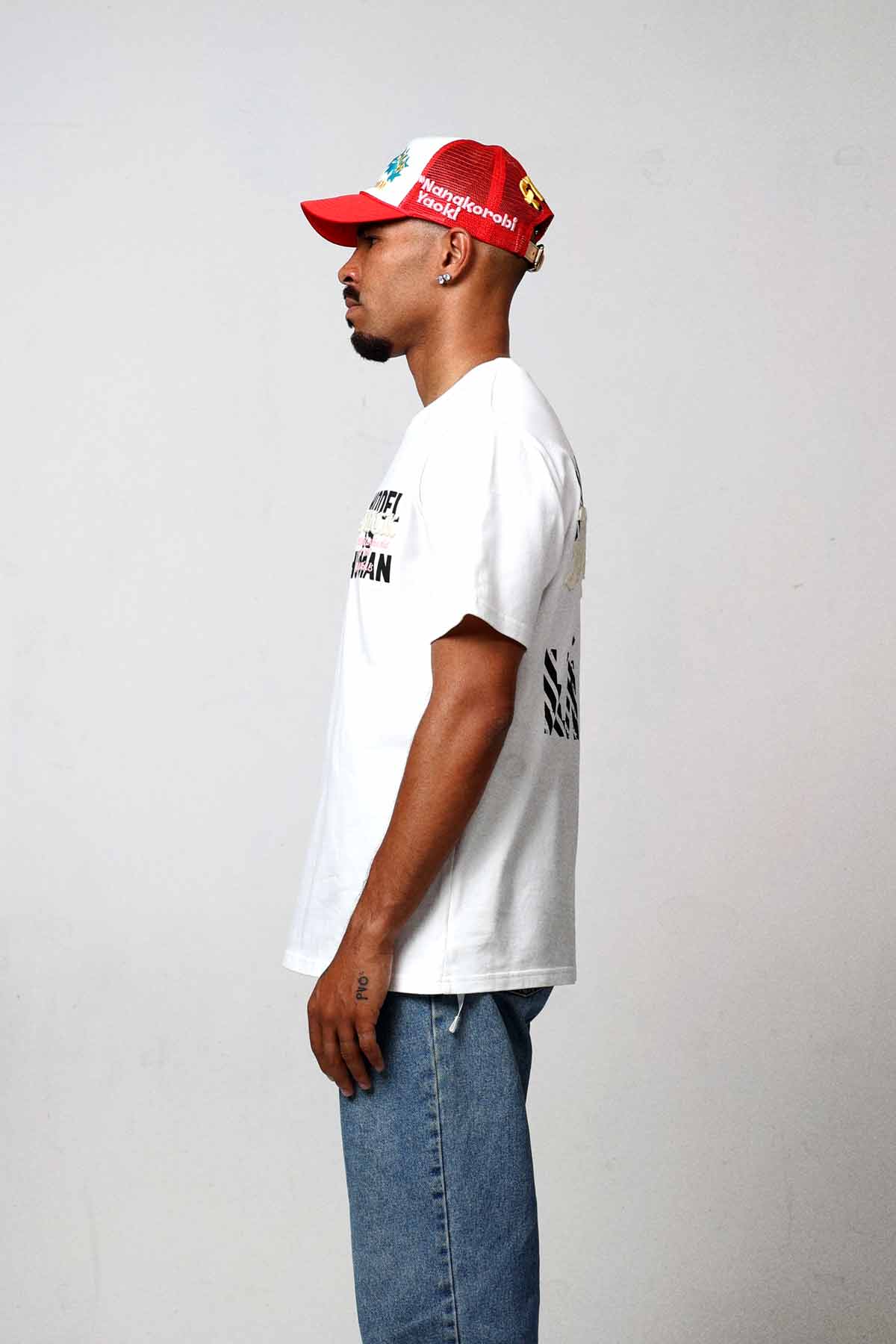 Man in white shirt and red cap, side view.