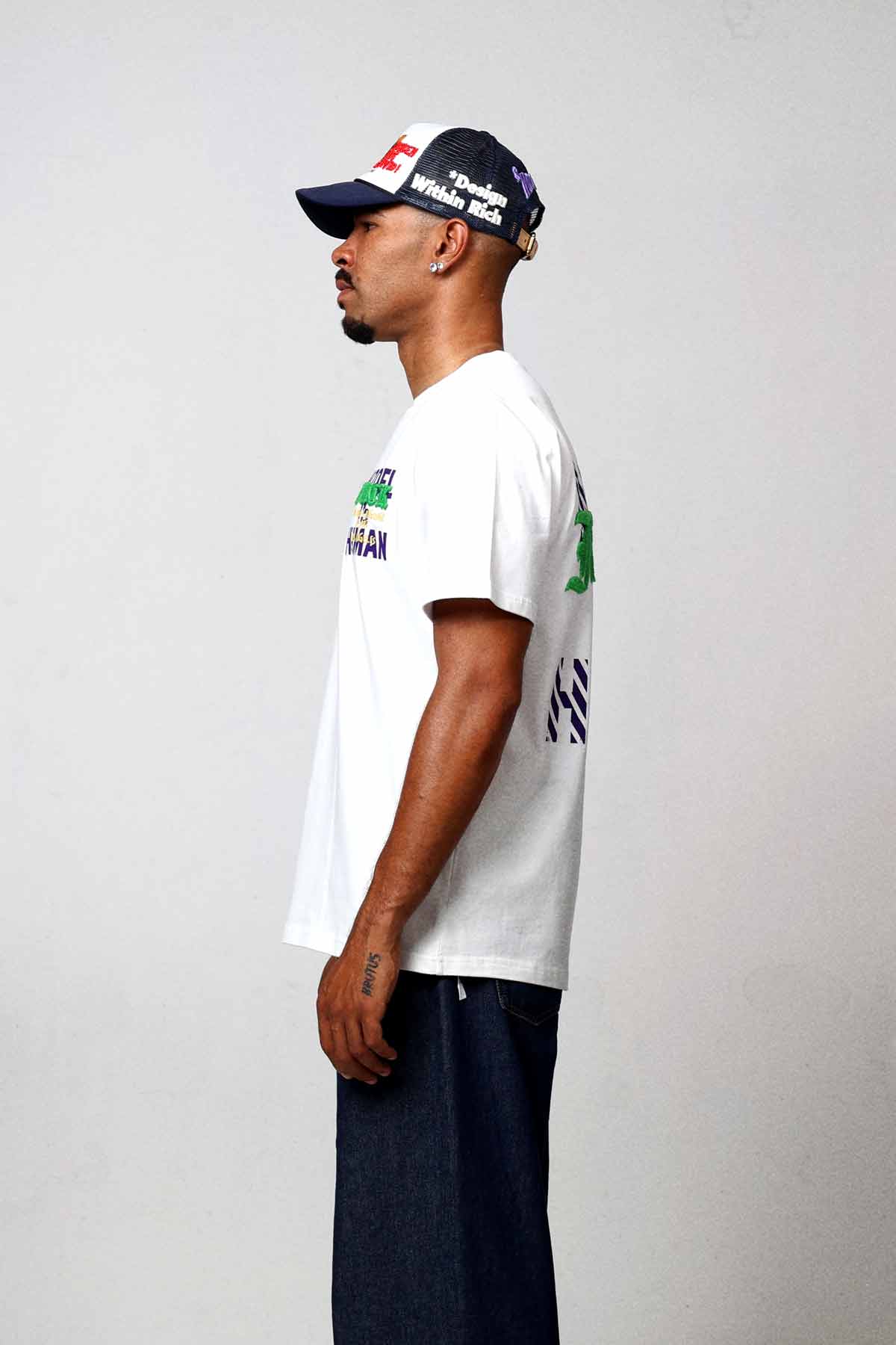 Man in white t-shirt and jeans, side view.