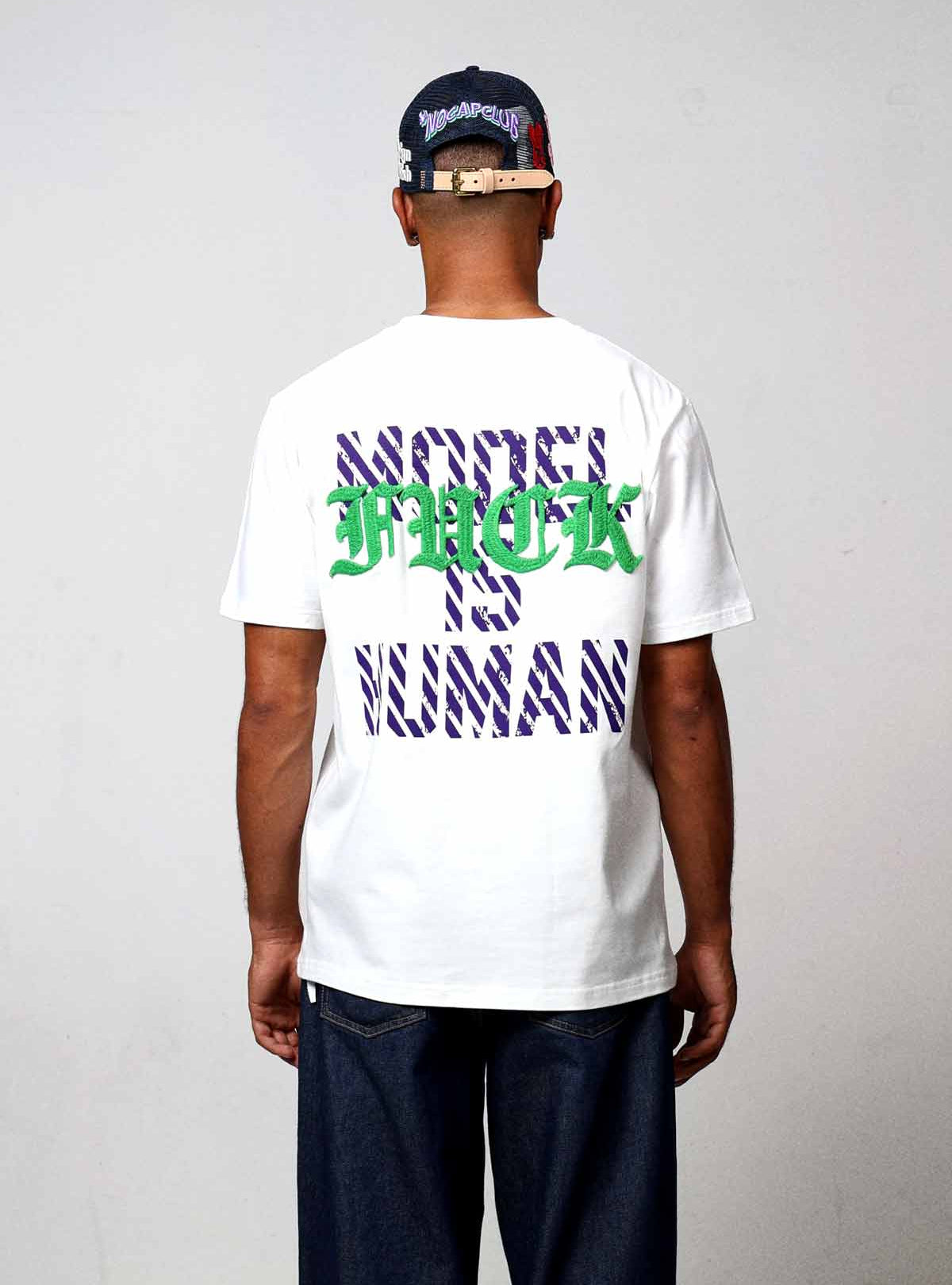 Man wearing graphic t-shirt and cap, back view.