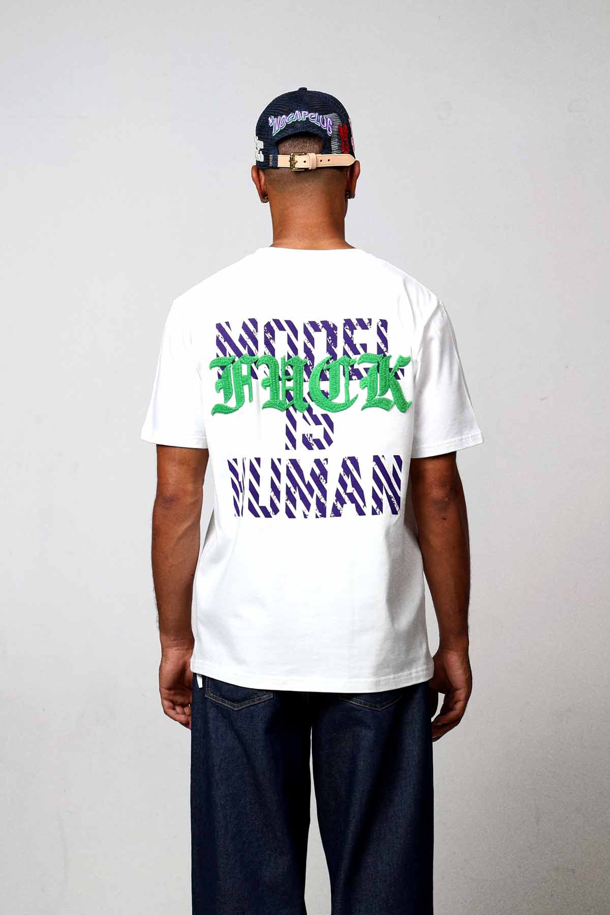 Man wearing graphic t-shirt and cap, back view.