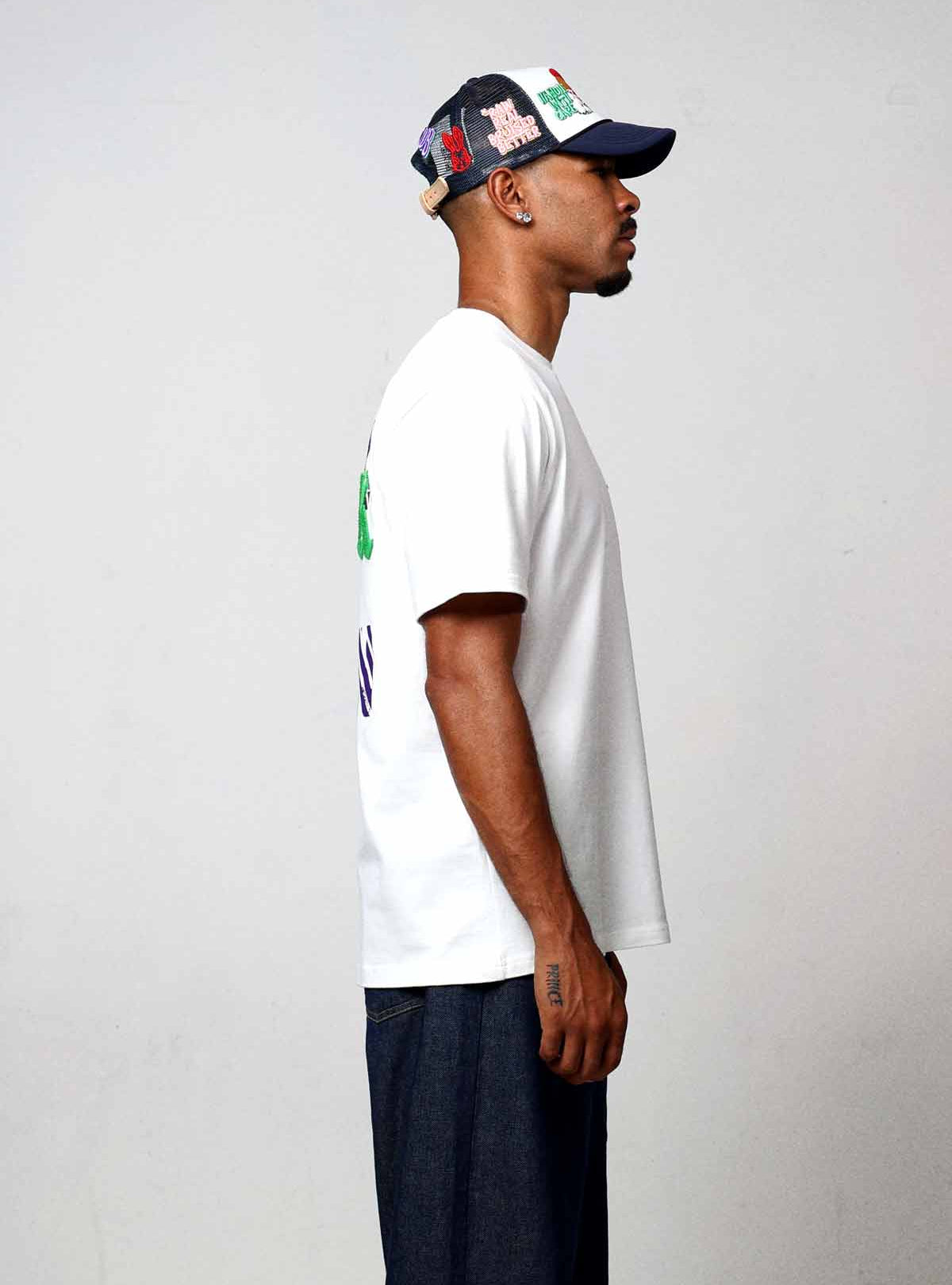 Man in white t-shirt and cap, side view.