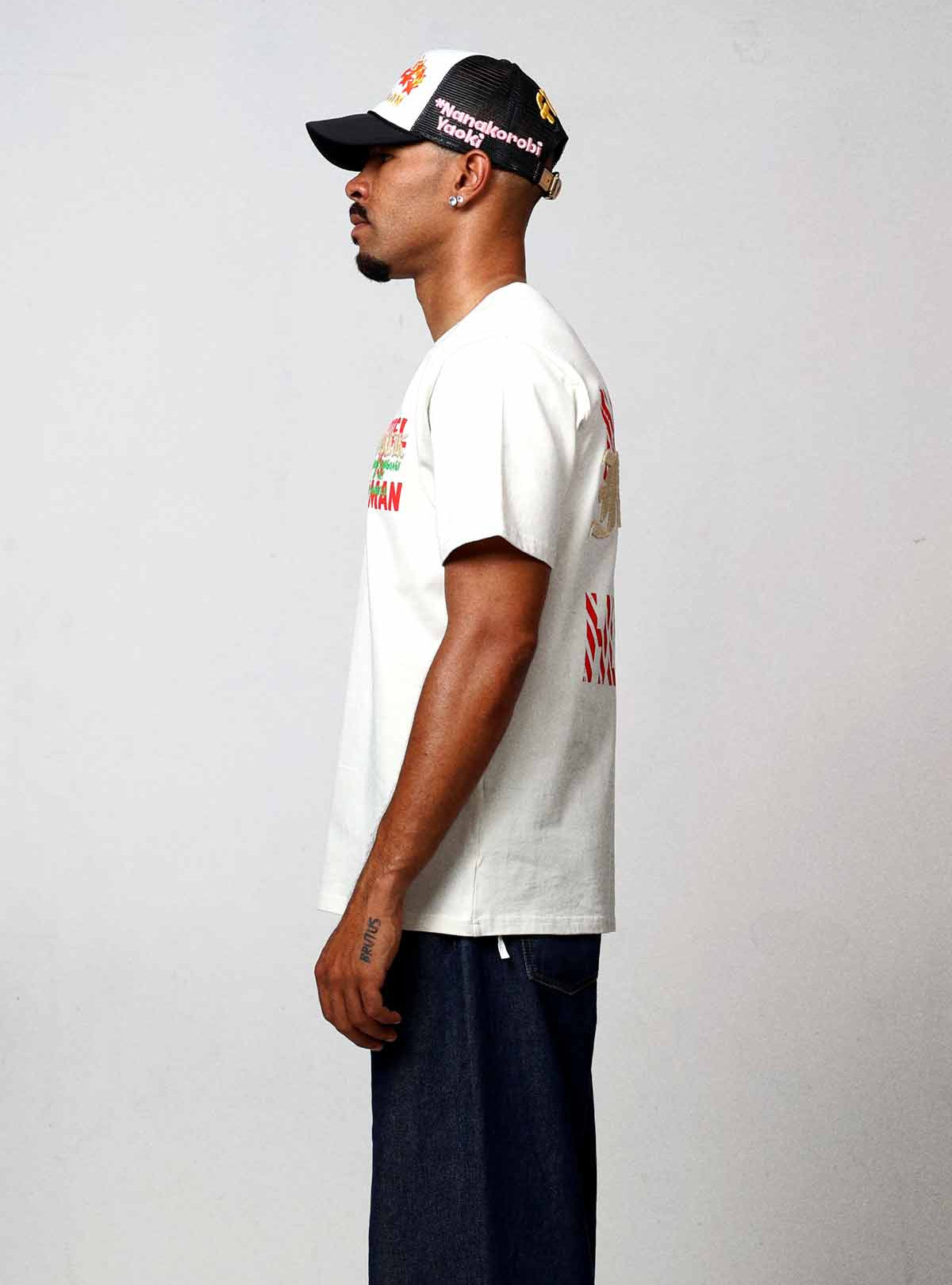 Man wearing white graphic t-shirt and black cap.