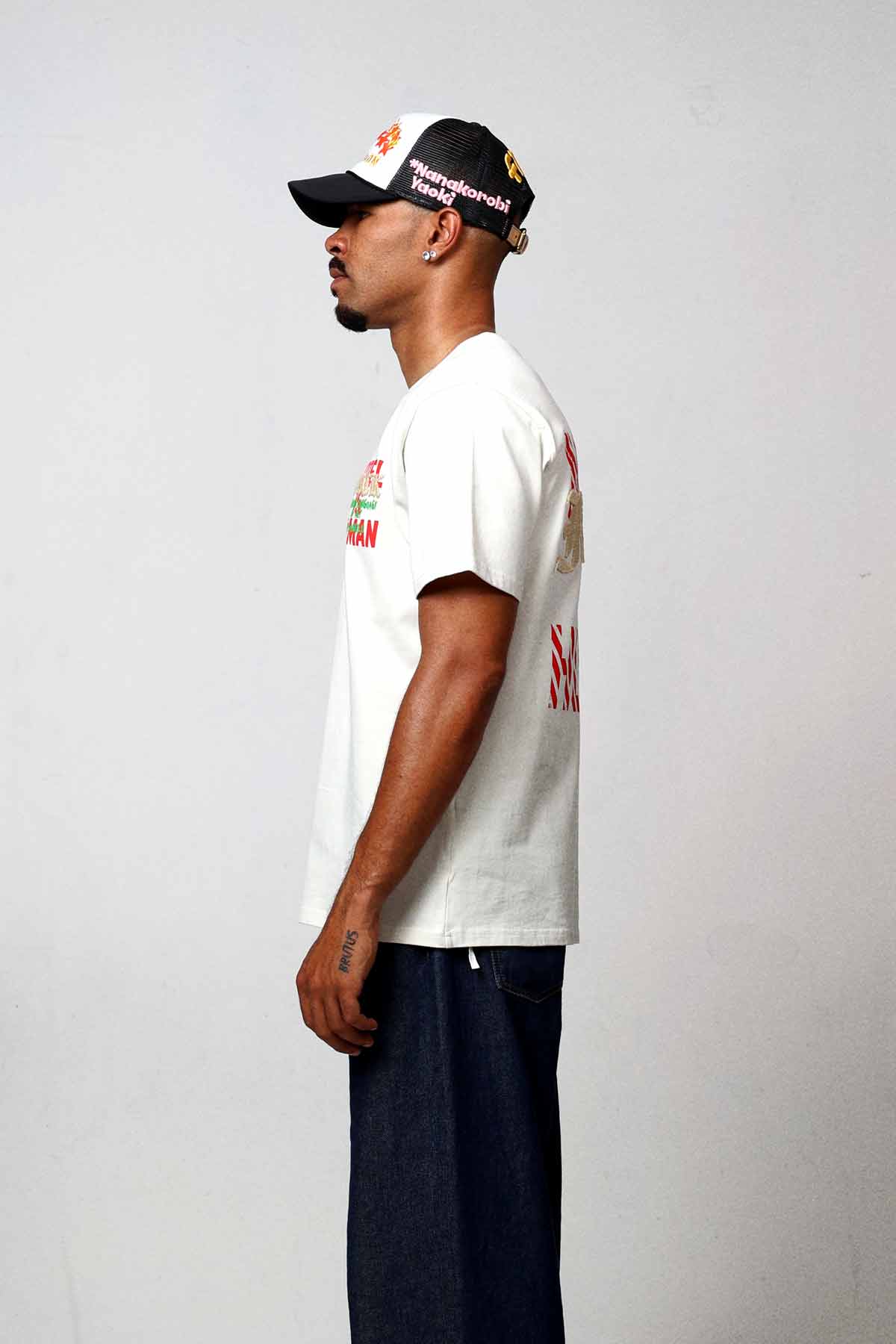 Man wearing white graphic t-shirt and black cap.