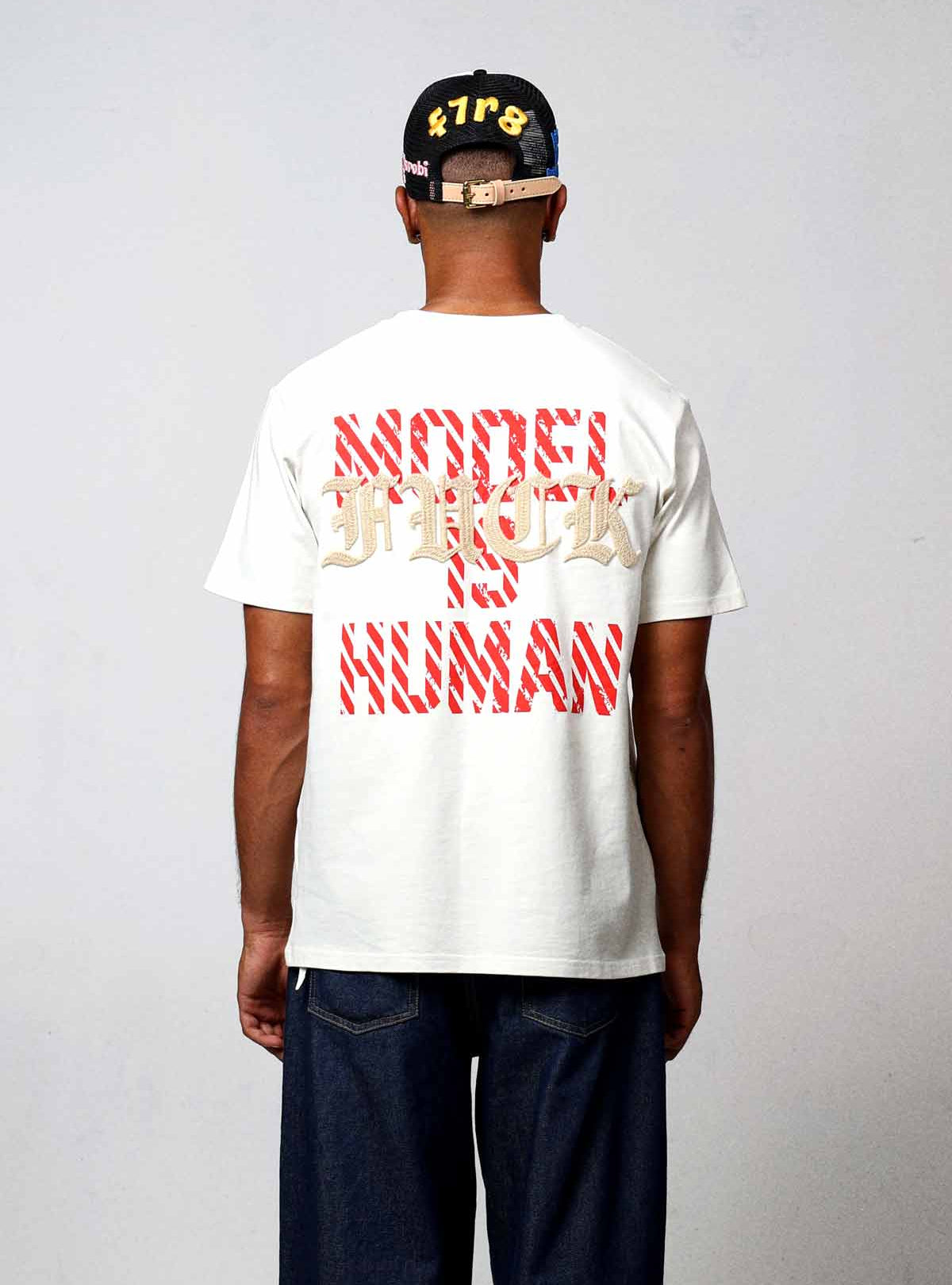 Man wearing graphic t-shirt and cap, back view.
