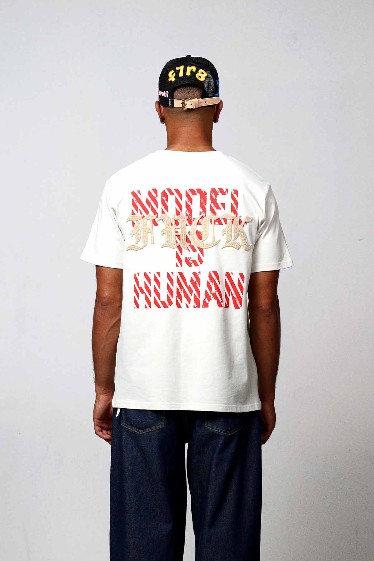 Man wearing graphic t-shirt and cap, back view.