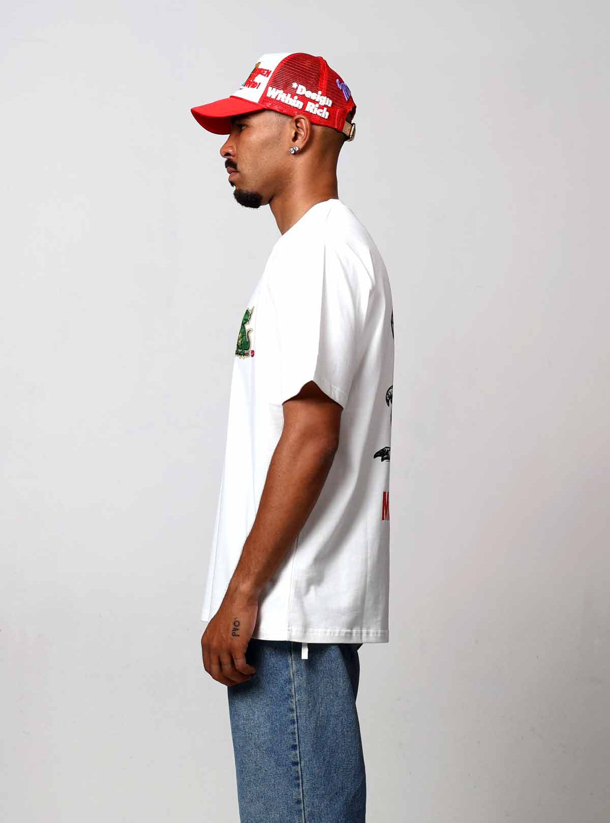 Man in white shirt and red cap, side view.