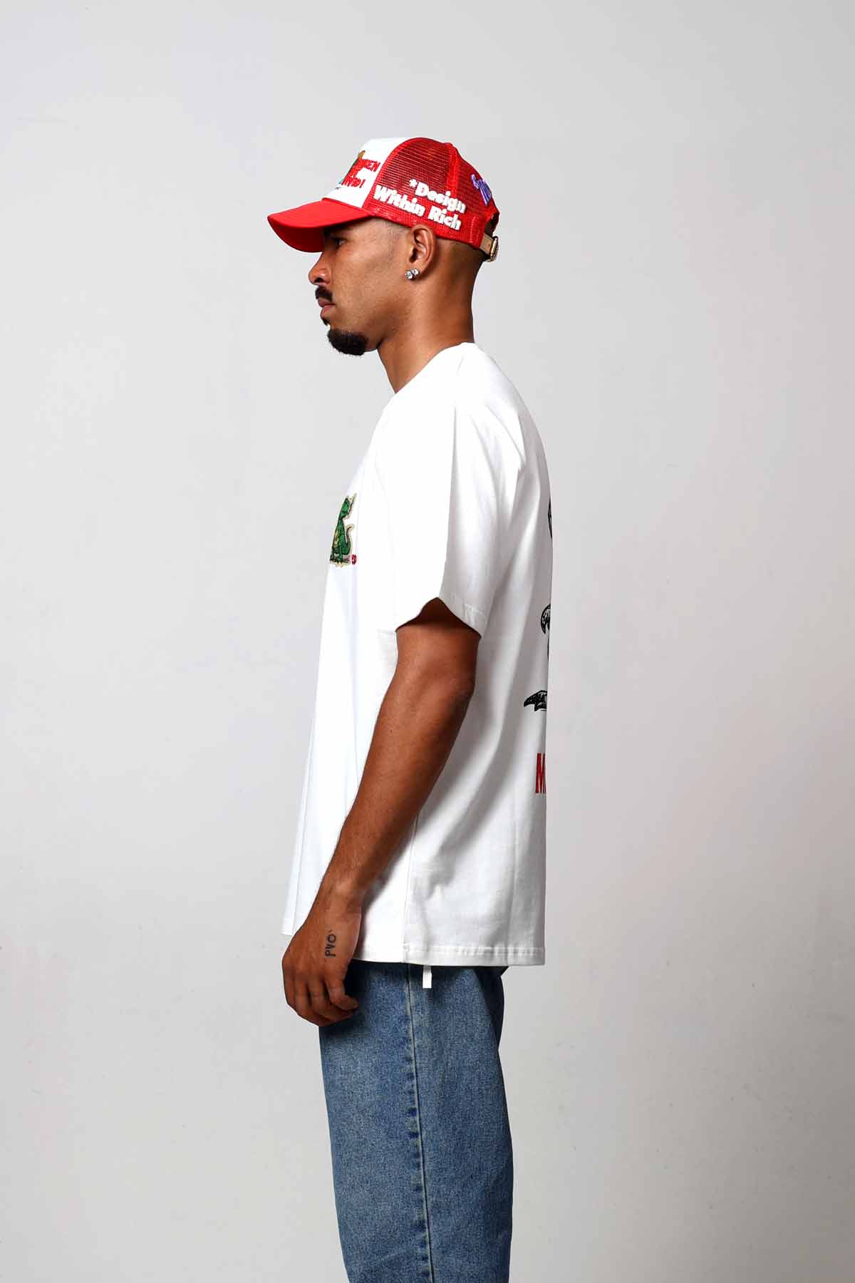 Man in white shirt and red cap, side view.