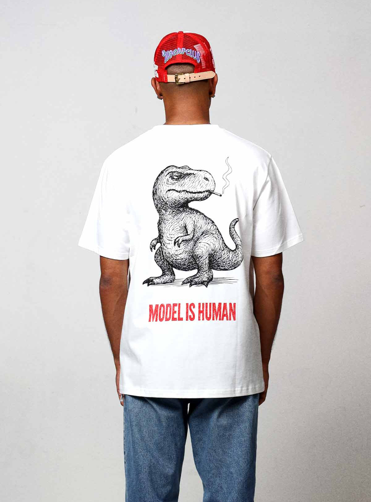 Man wearing dinosaur graphic t-shirt and red cap.