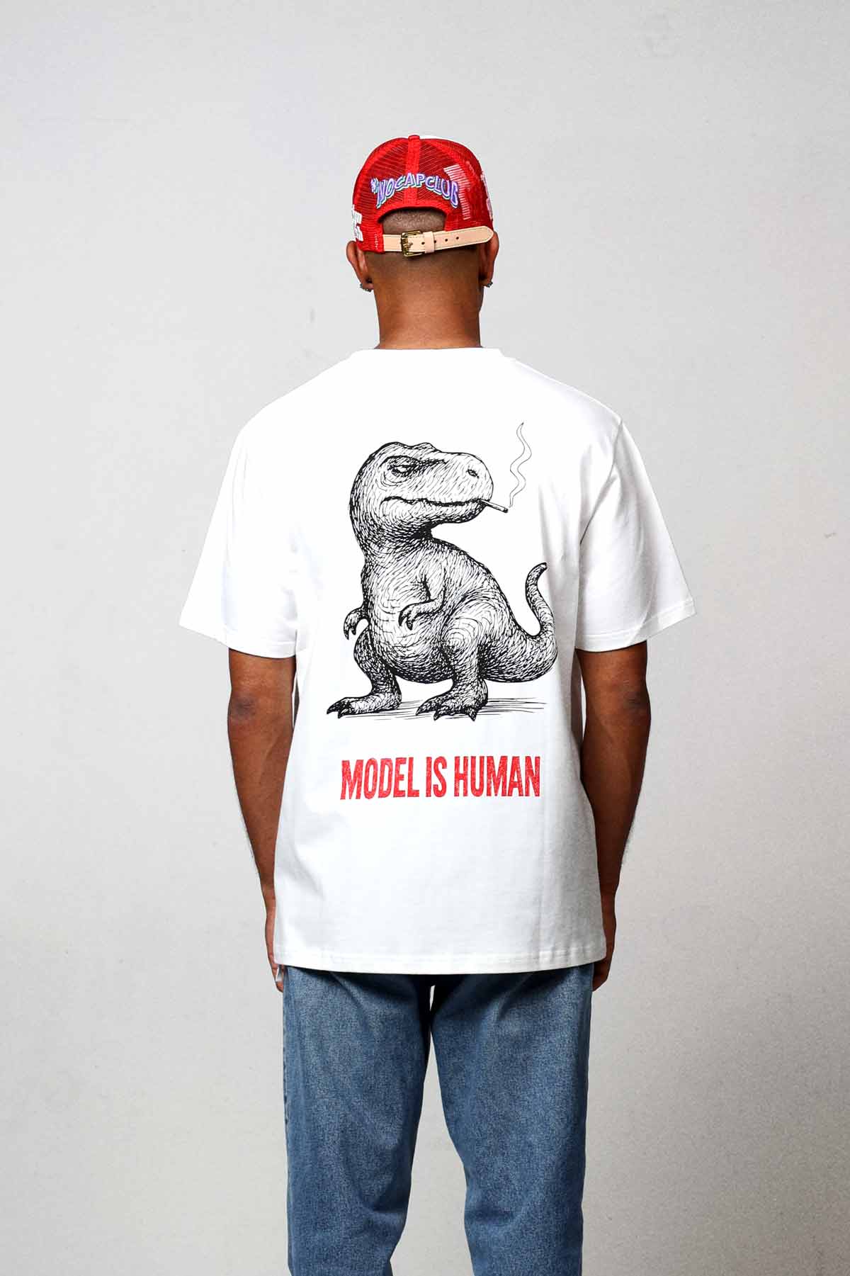 Man wearing dinosaur graphic t-shirt and red cap.