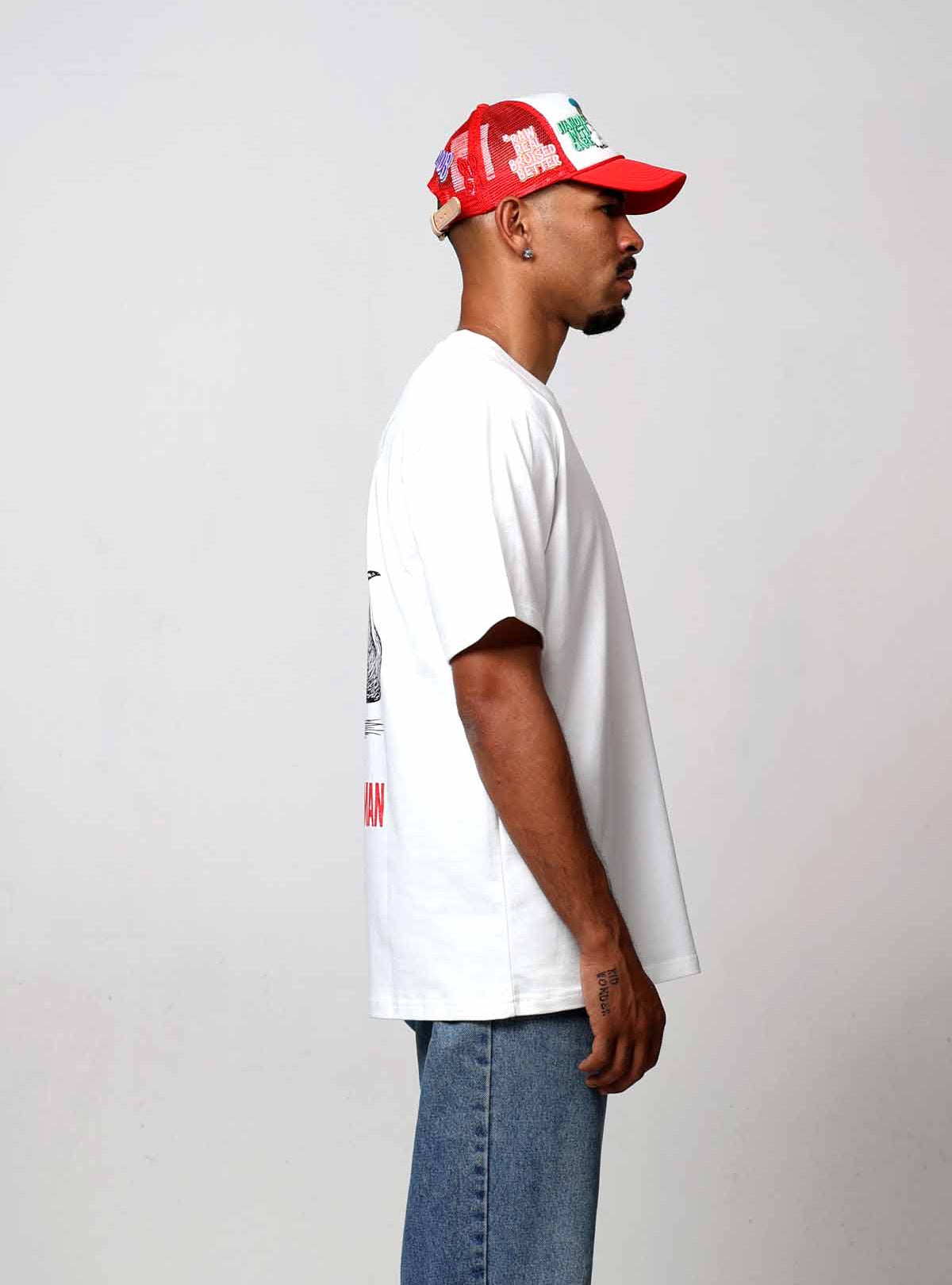 Man in white shirt and red cap, side view.
