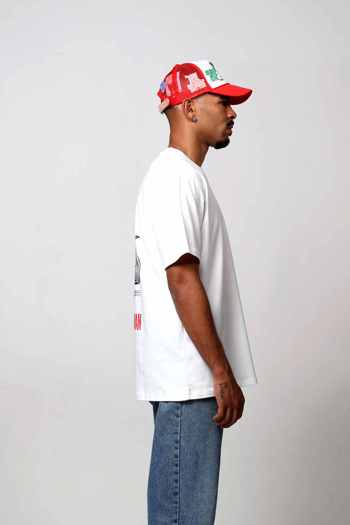 Man in white shirt and red cap, side view.