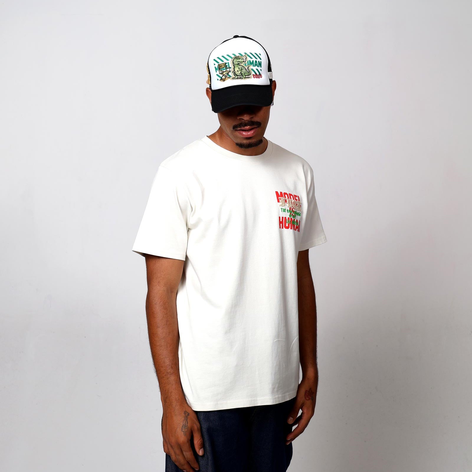 Man in white t-shirt and cap with graphic designs.