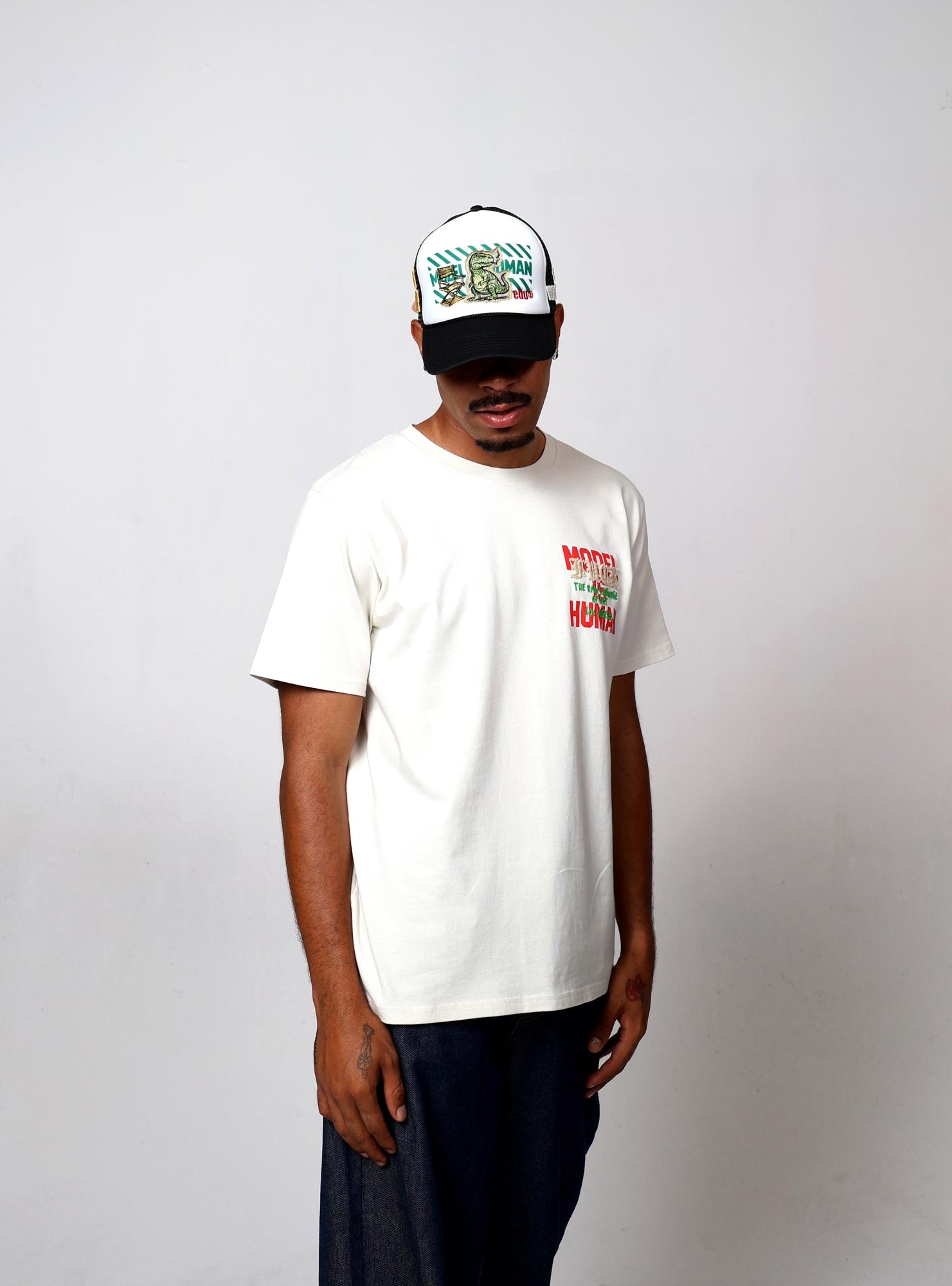 Man in white t-shirt and cap with graphic designs.