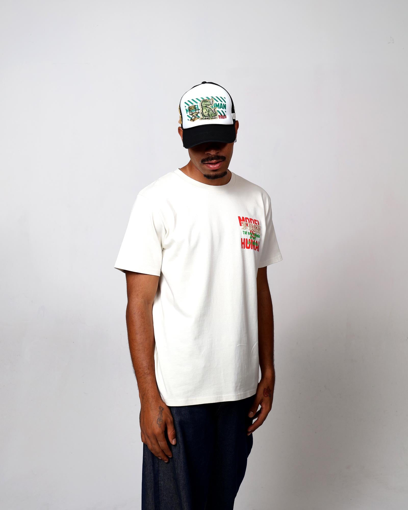 Man in white t-shirt and cap with graphic designs.