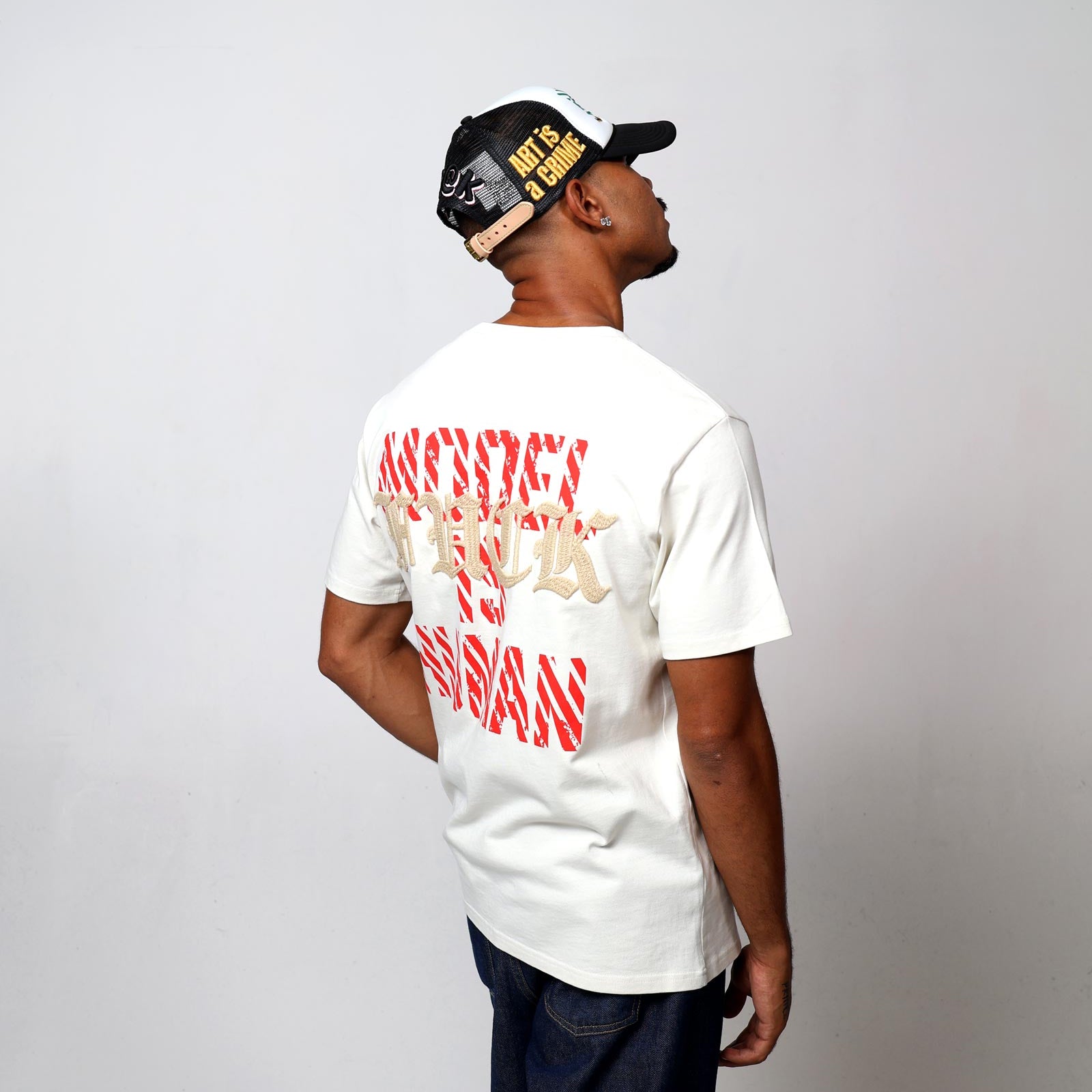 Man in cap and graphic t-shirt, standing sideways.