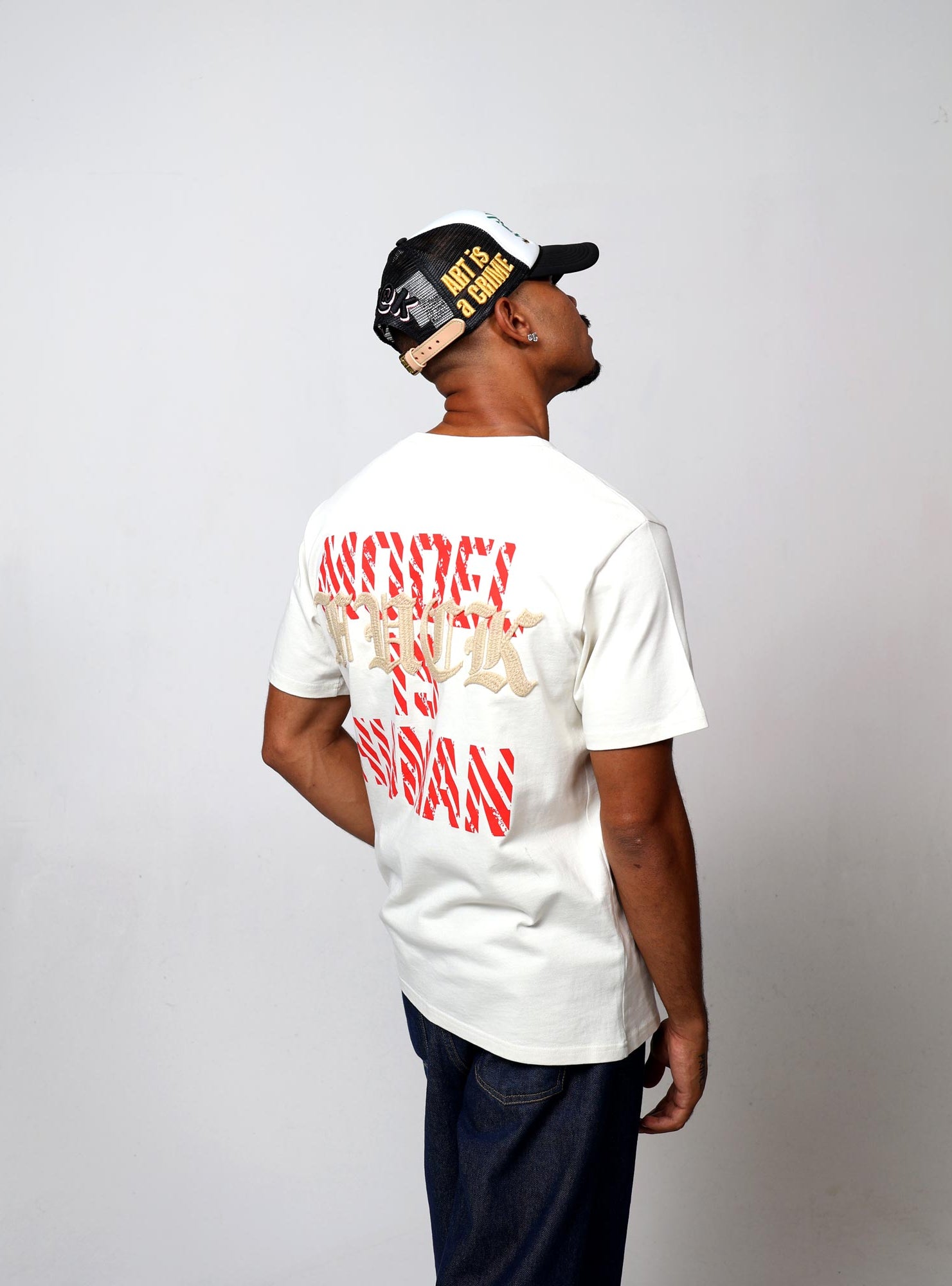 Man in cap and graphic t-shirt, standing sideways.