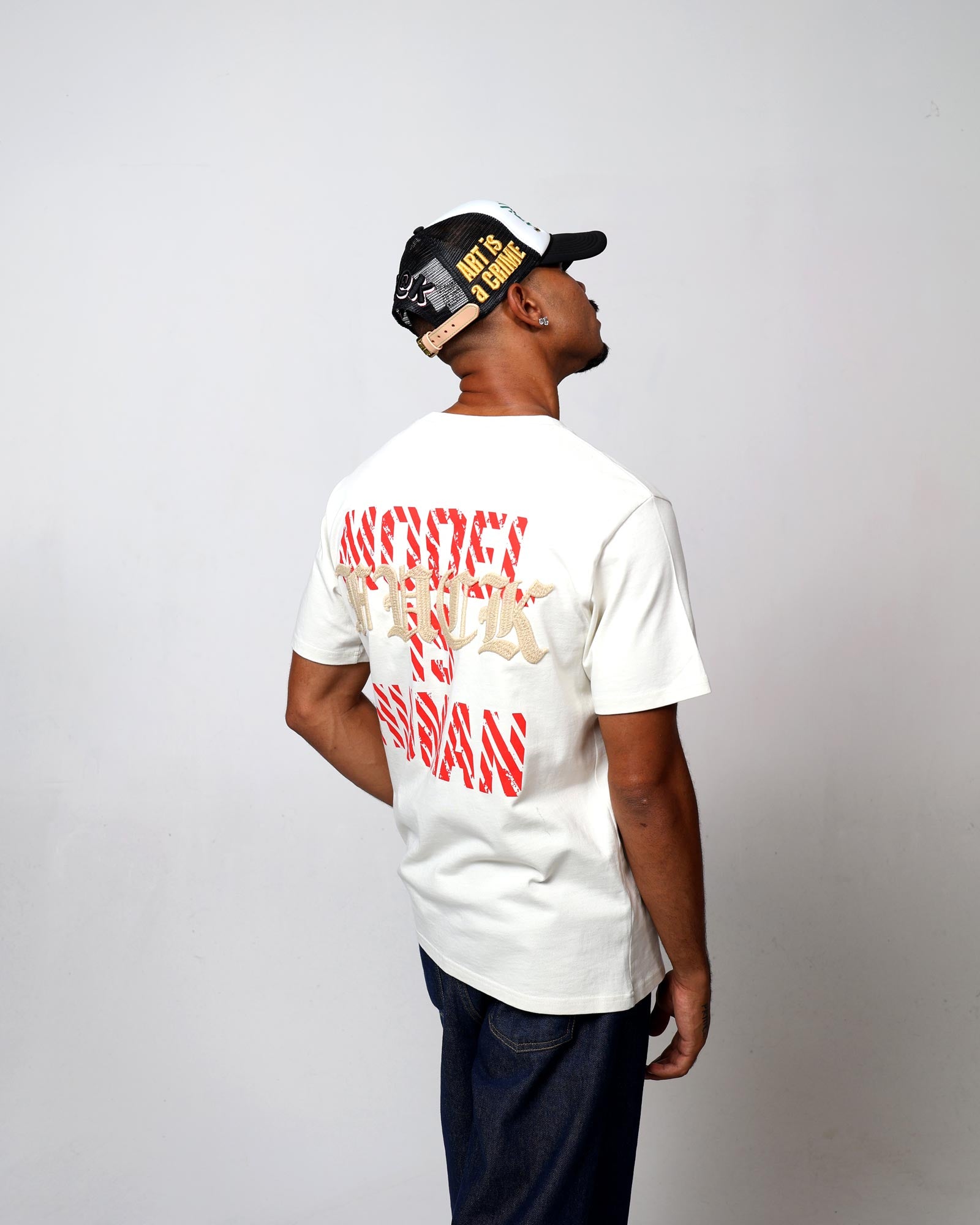 Man in cap and graphic t-shirt, standing sideways.