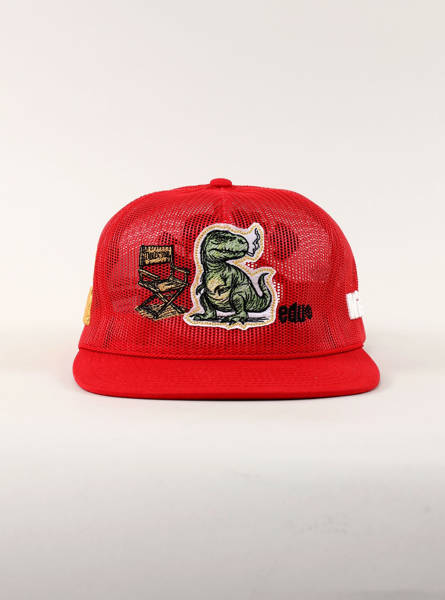Red cap with dinosaur and film reel patches.