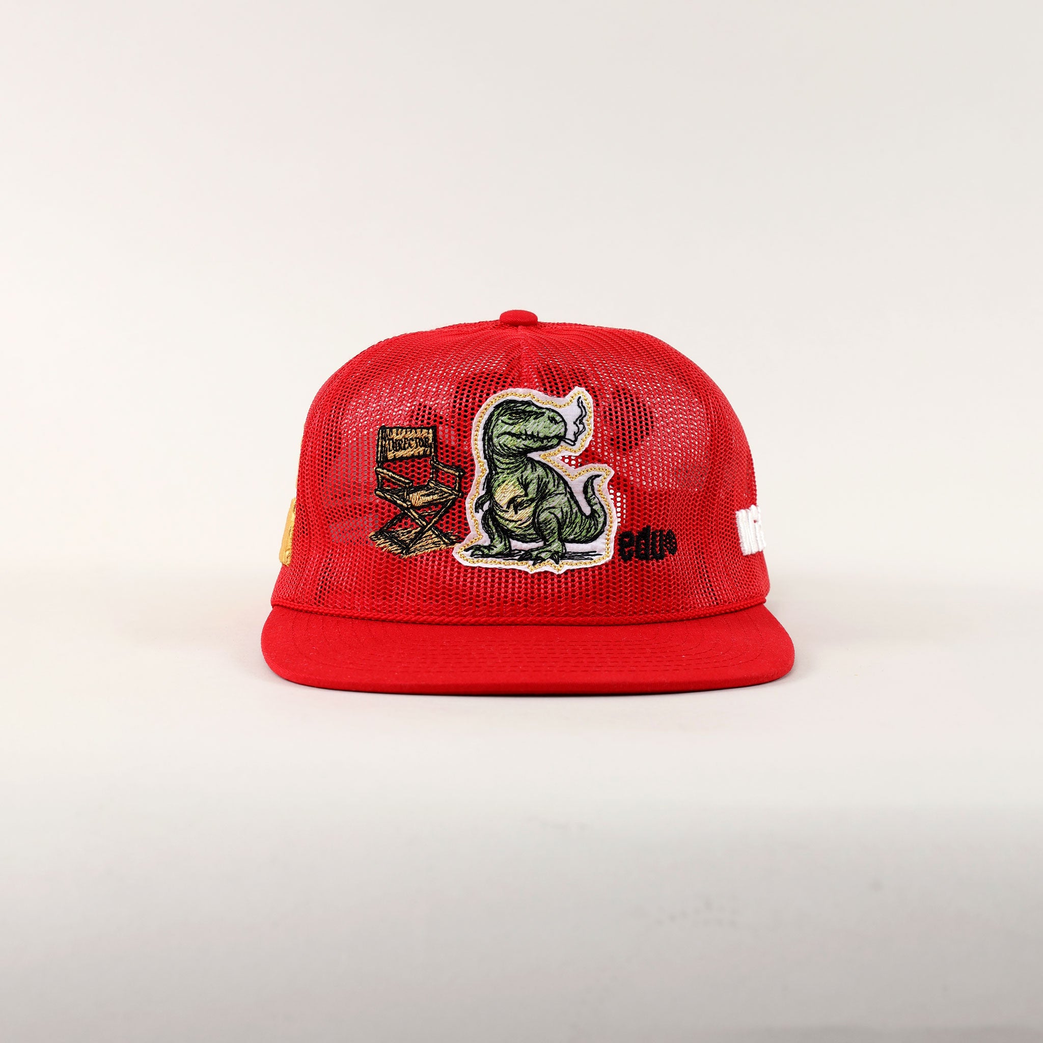 Red cap with dinosaur and film reel patches.