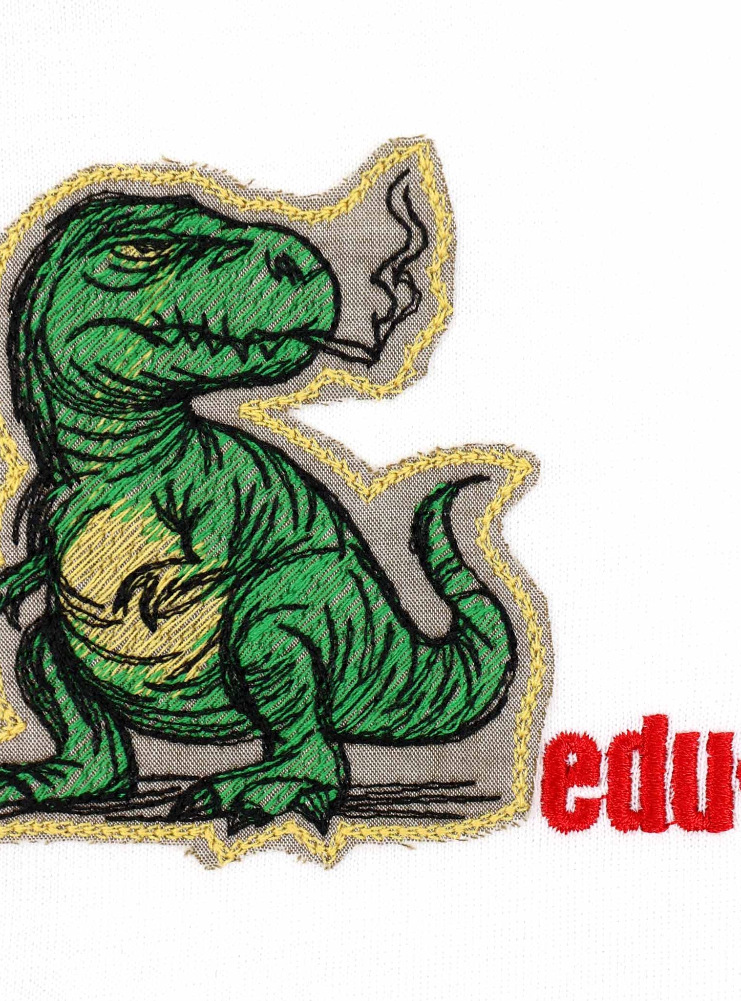Green dinosaur smoking, embroidered on fabric.
