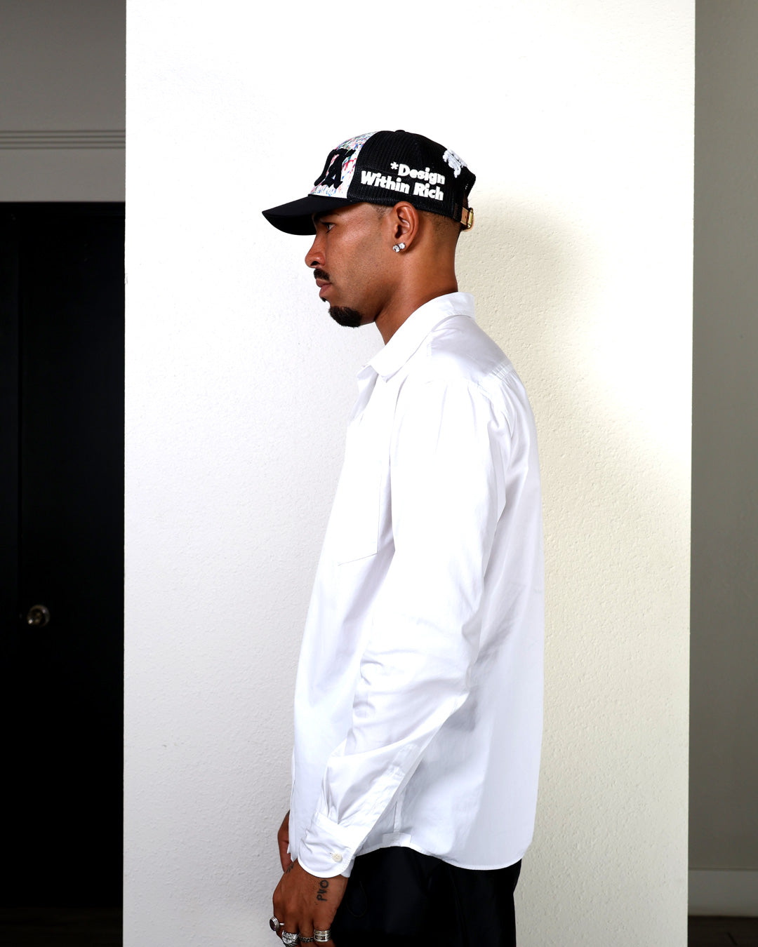 Man wearing a white shirt and black cap with visible branding