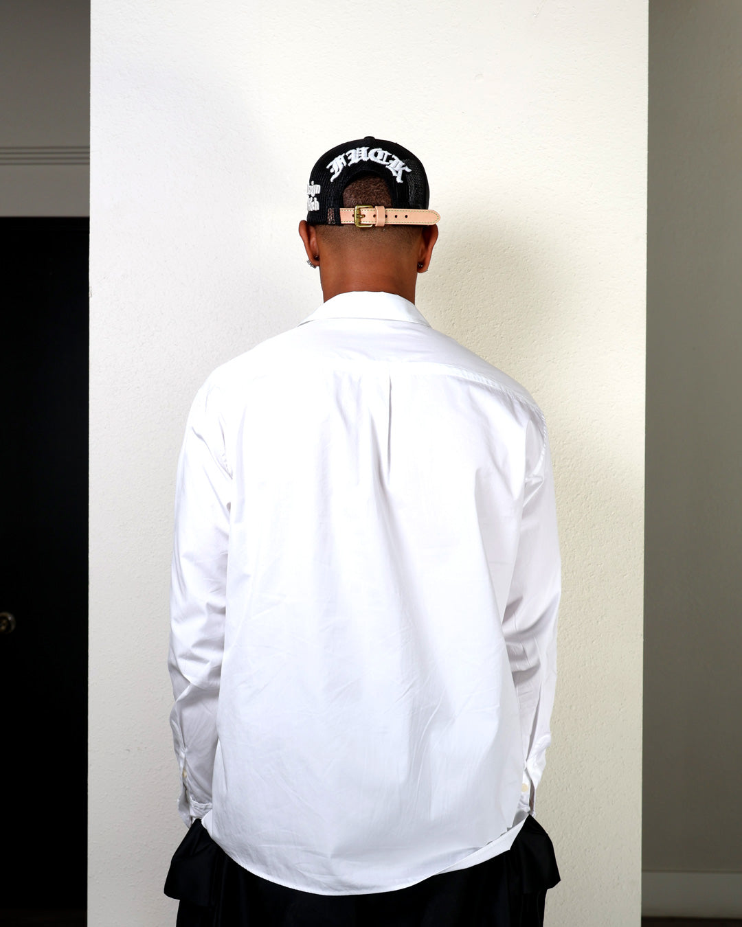 Person wearing a white shirt and black cap
