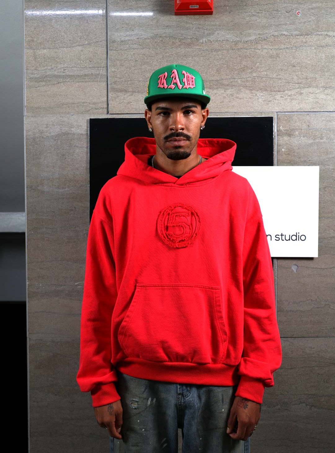 Man in red hoodie and green cap.